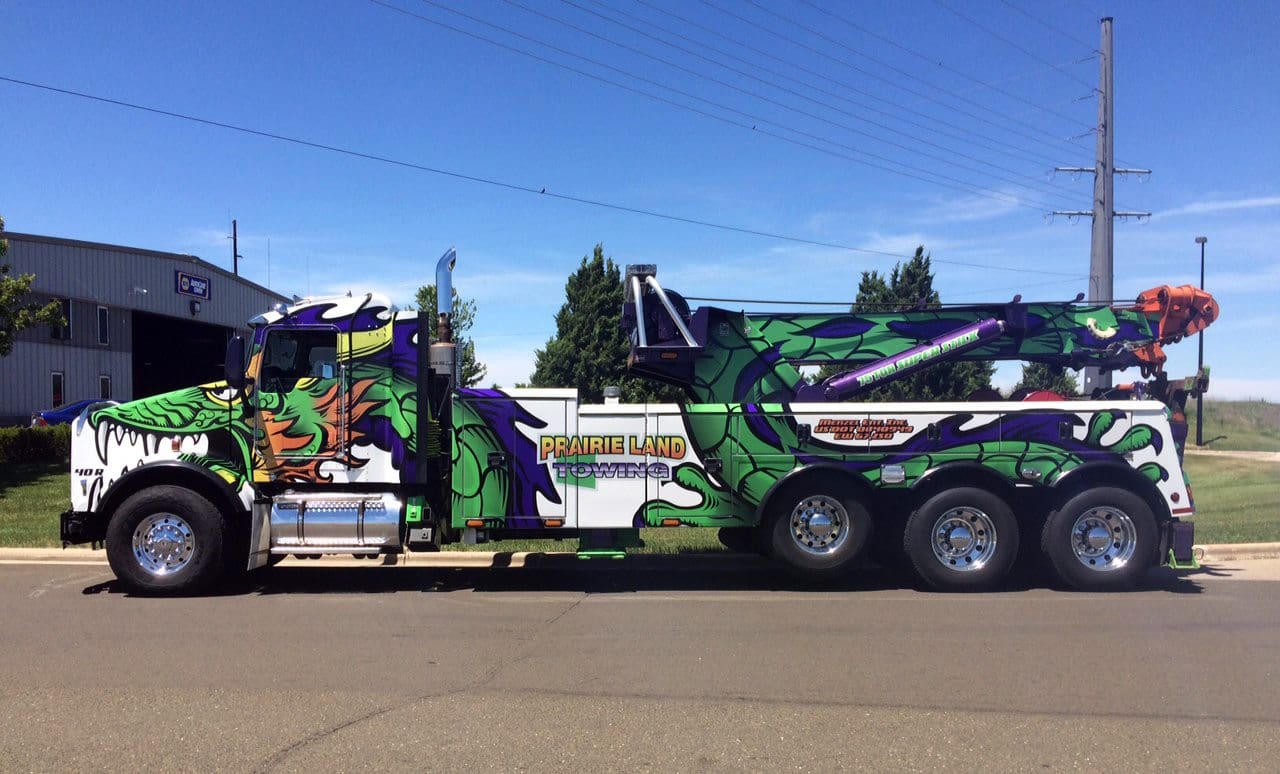 Company towing truck with purple and green dragon vehicle wrap to promote a fun and exciting business