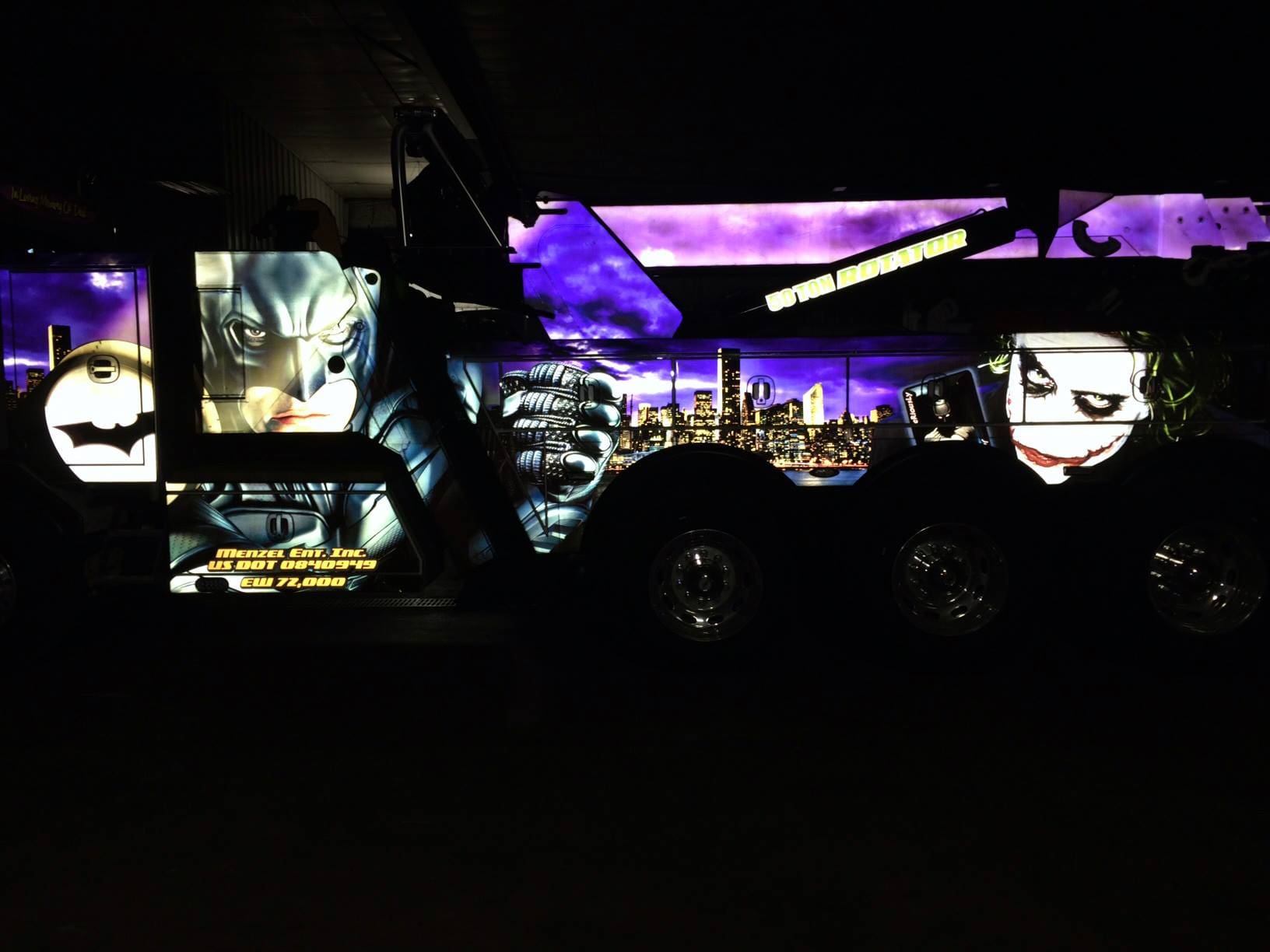 Glowing DC comics truck wrap design on the side of a towing truck