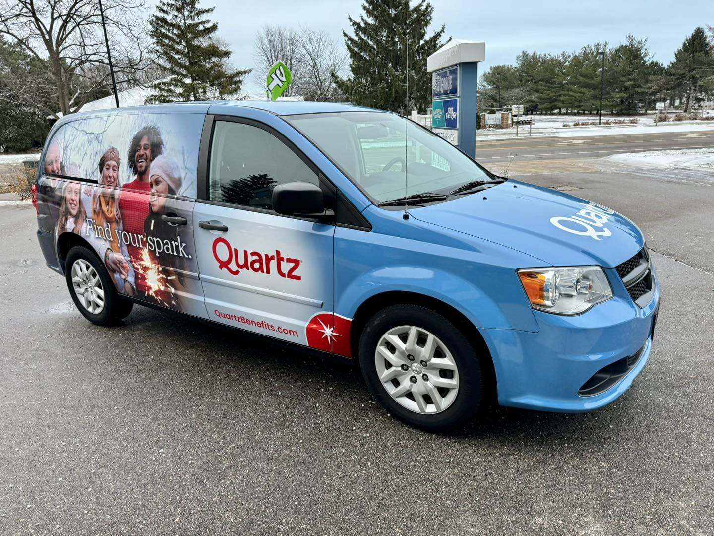 Quartz benefits company van with blue Fleet Graphics Vehicle wrap designed by Madison Graphics Company featuring a smiling family in the snow
