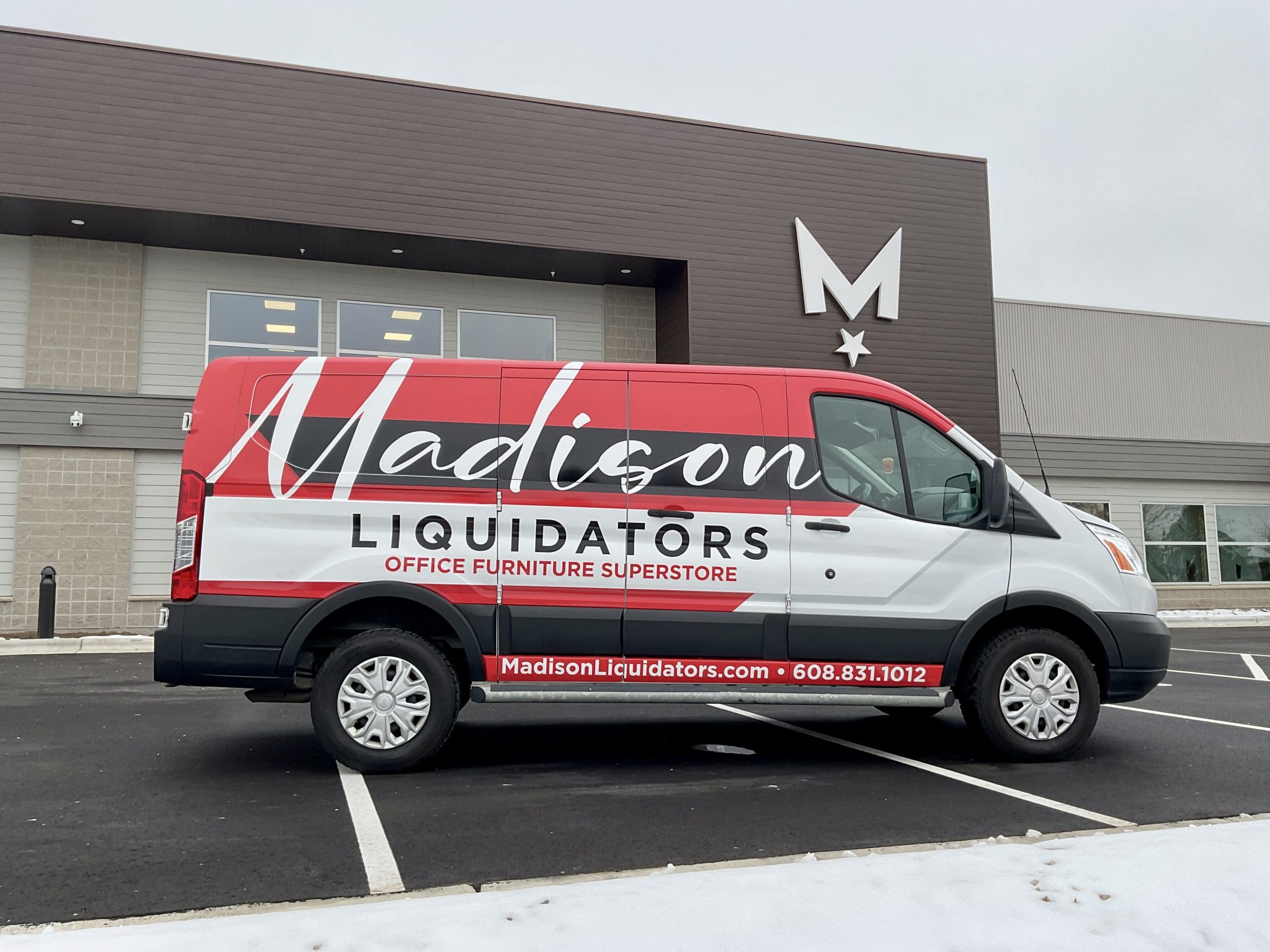 Madison Liquidators van, featuring custom fleet graphics, is parked in front of Madison Graphics Company design building. The van advertises “Office Furniture Superstore” plus phone and website