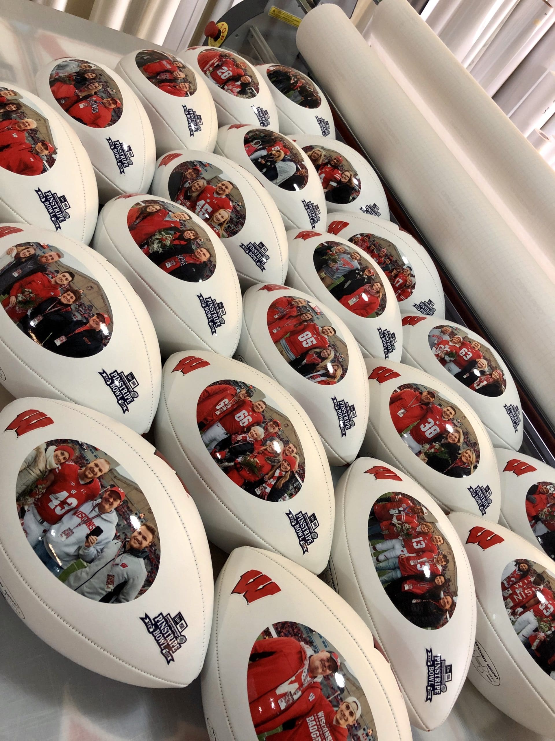White footballs with UW-Madison W logo and images of football families printed on the side