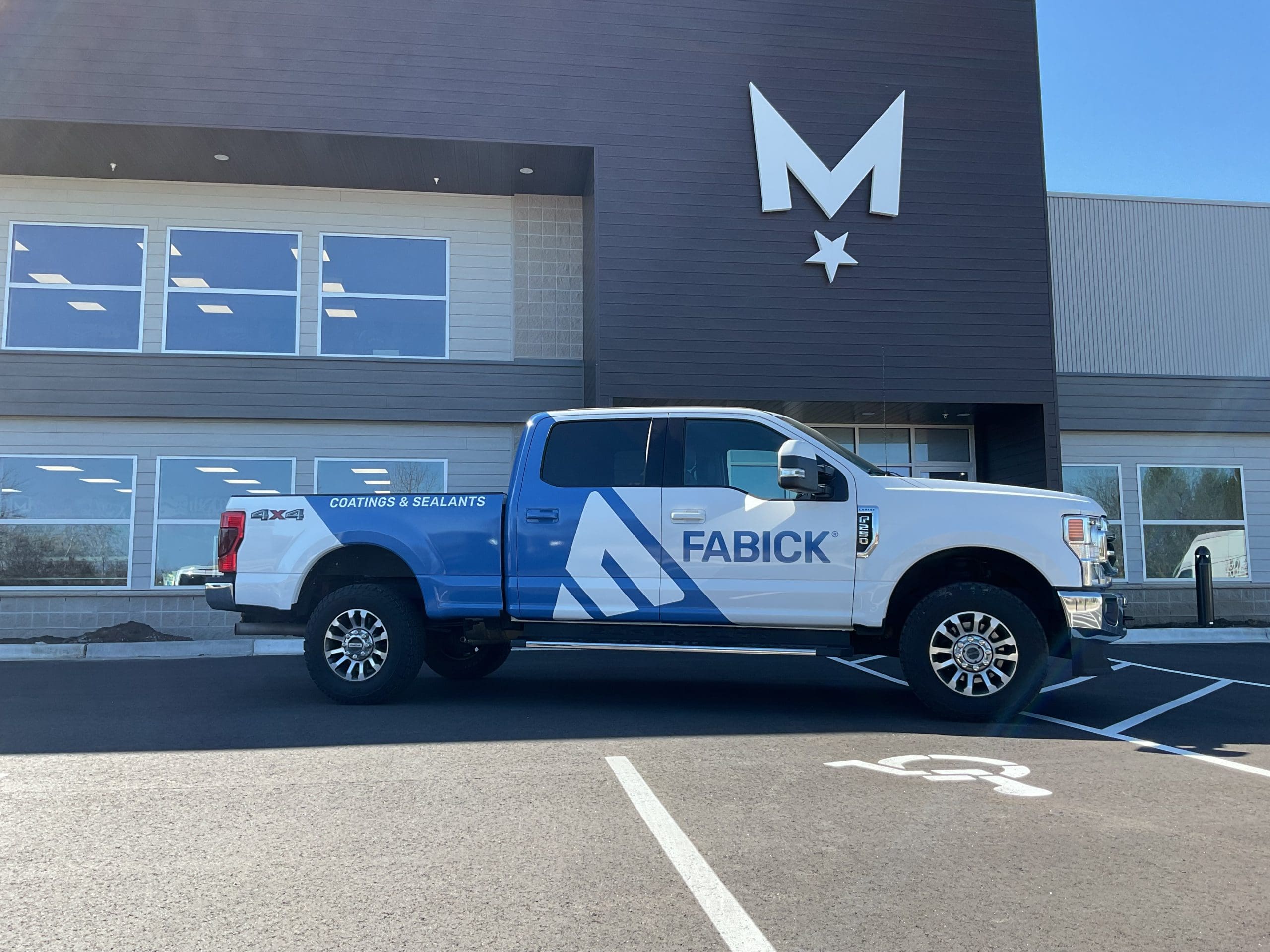 Fabick company truck with Fleet Graphics Vehicle wrap designed by Madison Graphics Company parked in front of the design building