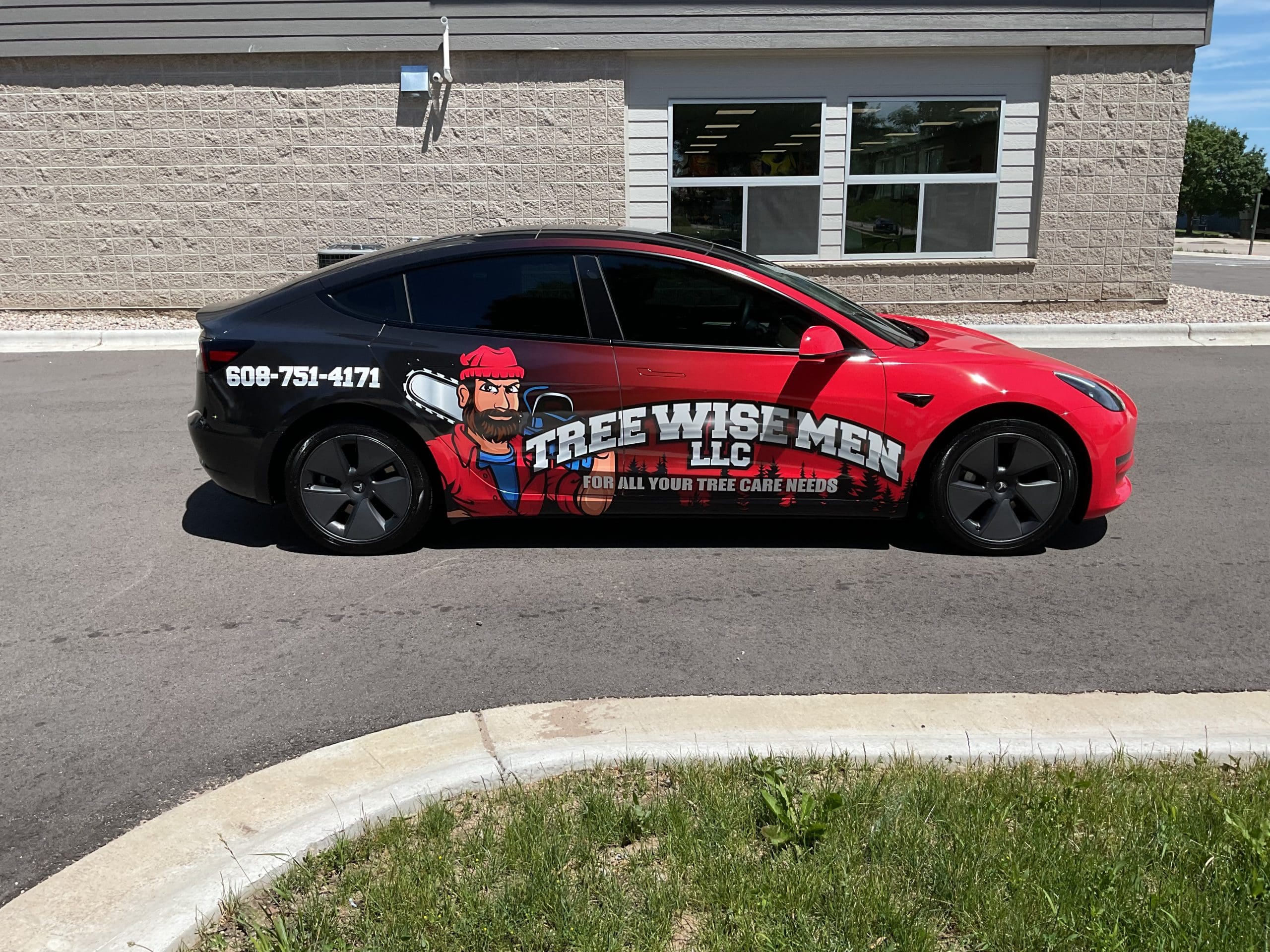Tree wise men company Tesla model 3 with cartoon lumberjack Fleet Graphics Vehicle wrap designed by Madison Graphics Company