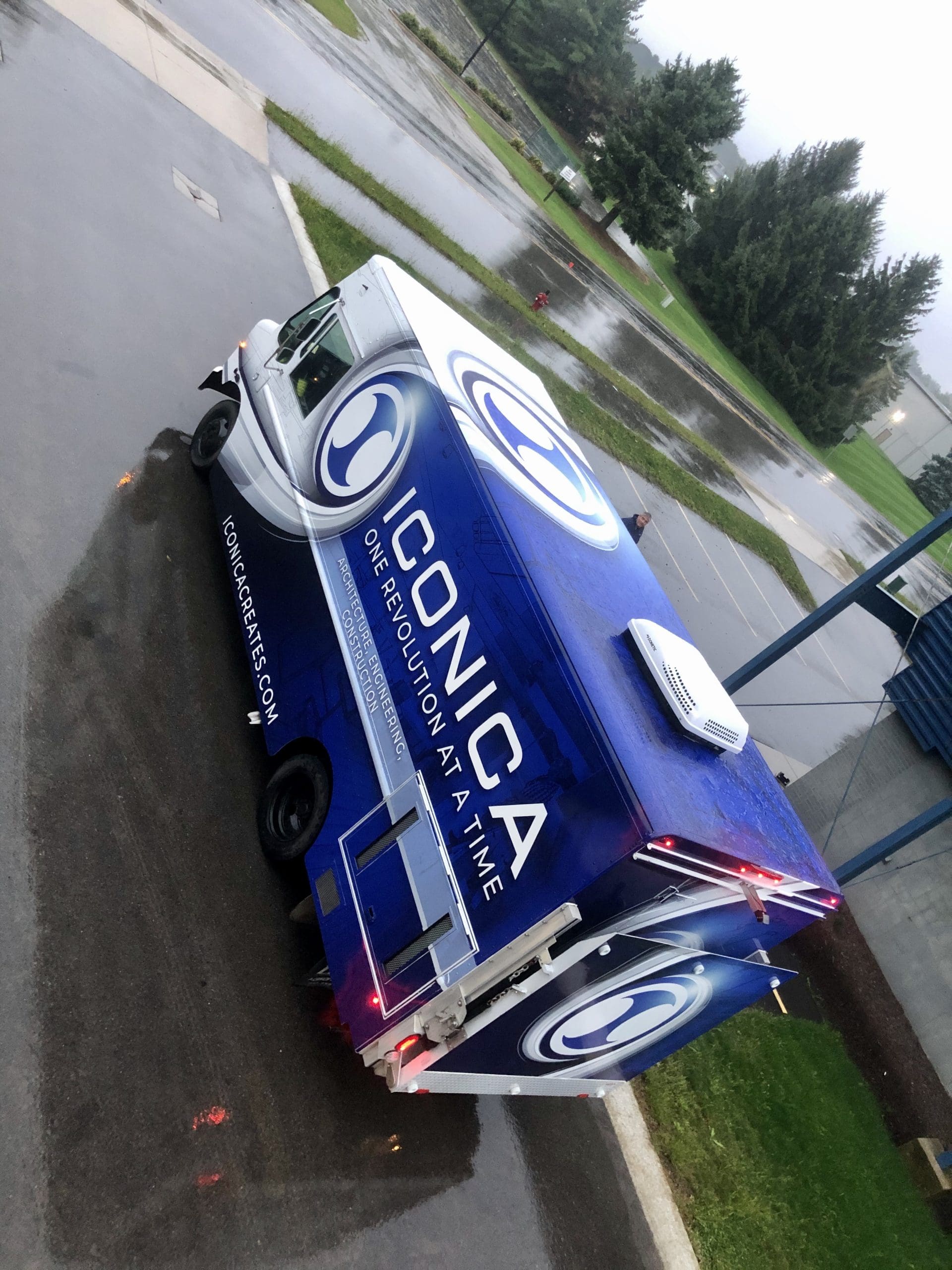 Iconica construction company truck with dark blue and white Fleet Graphics Vehicle wrap designed by Madison Graphics Company parked in a rainy lot