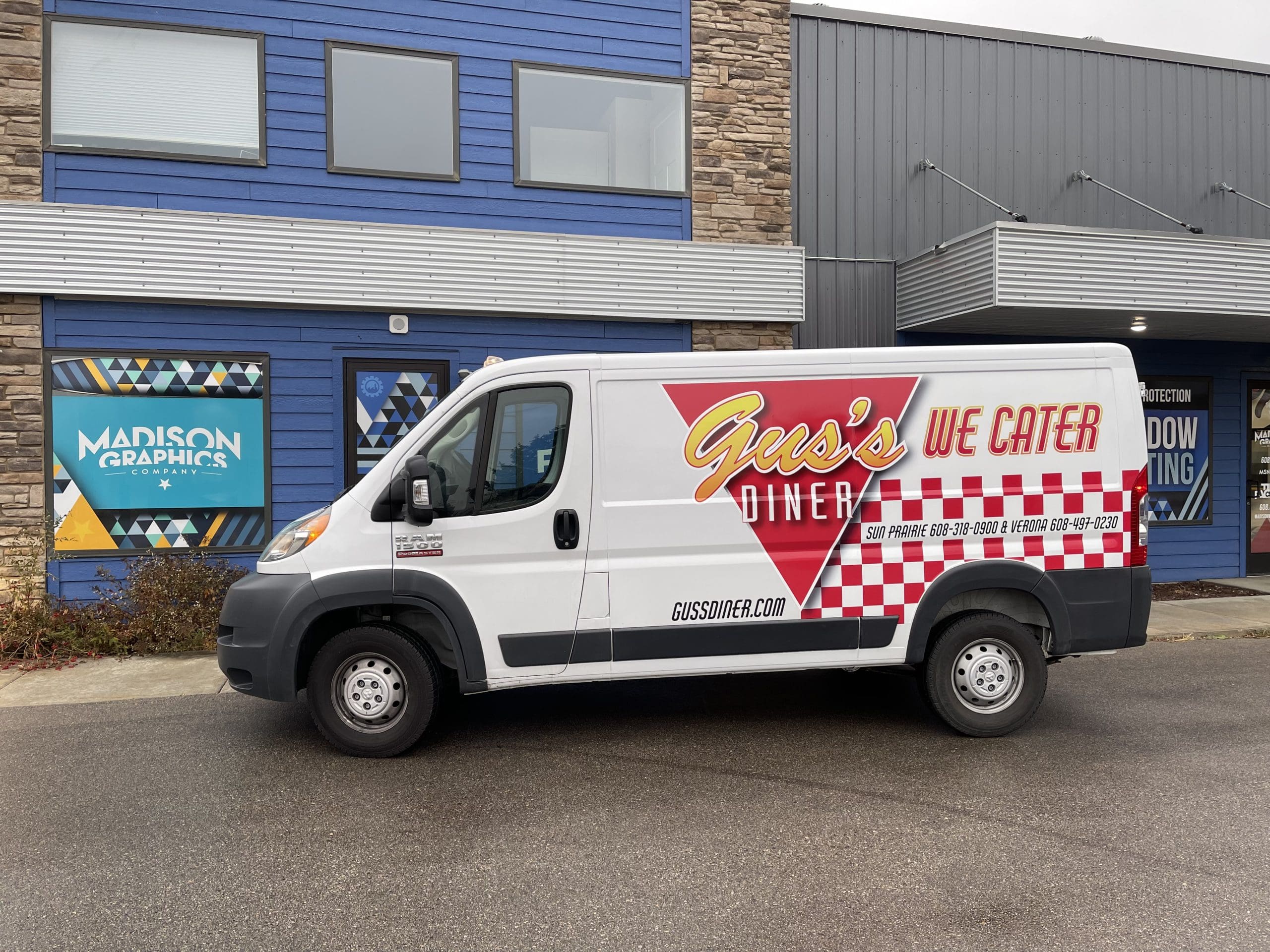 Gus's Diner company van with Fleet Graphics Vehicle wrap designed by Madison Graphics Company parked in front of the design building