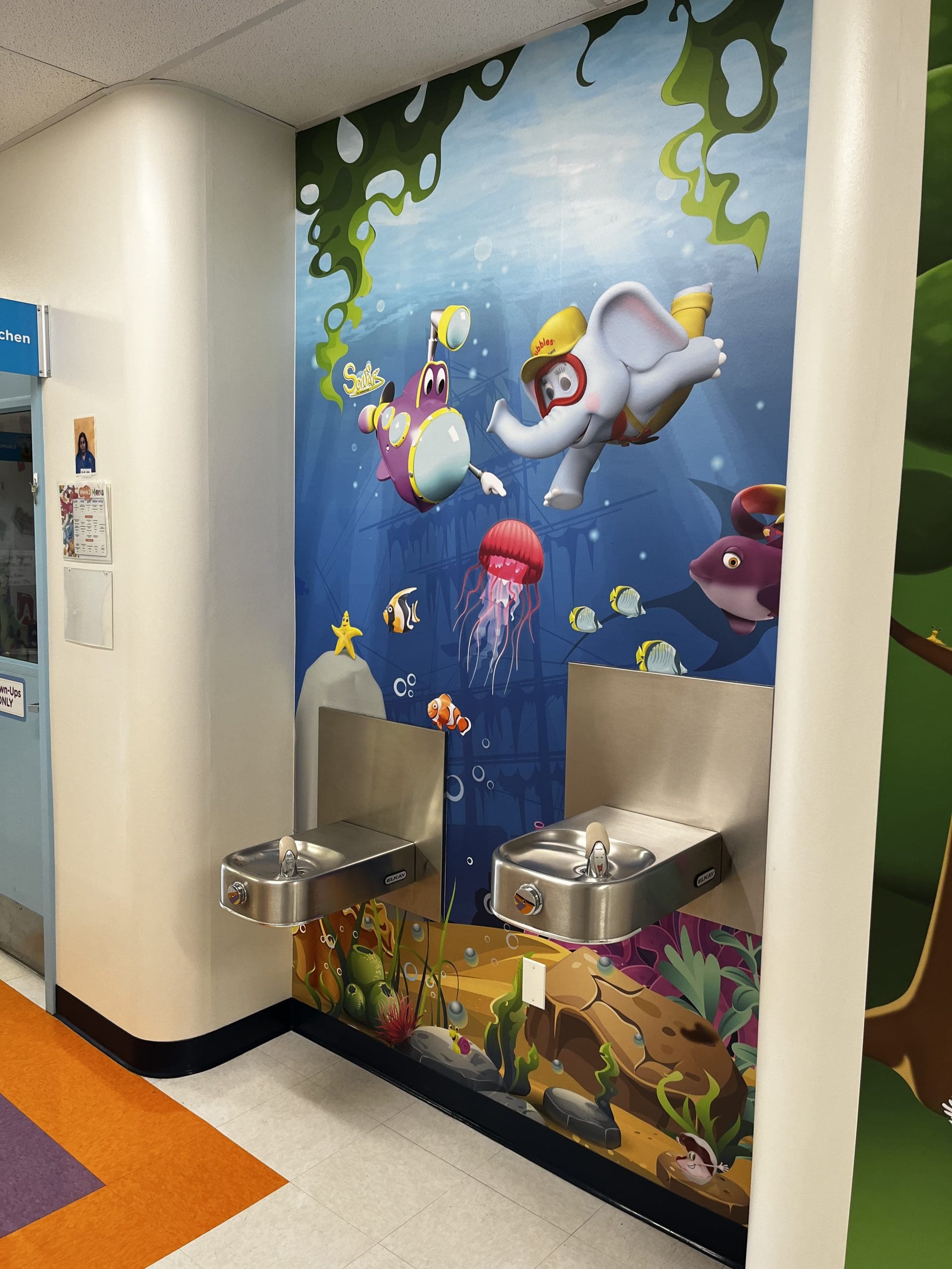 Cartoons Graphics banner on wall behind a water fountain in a school