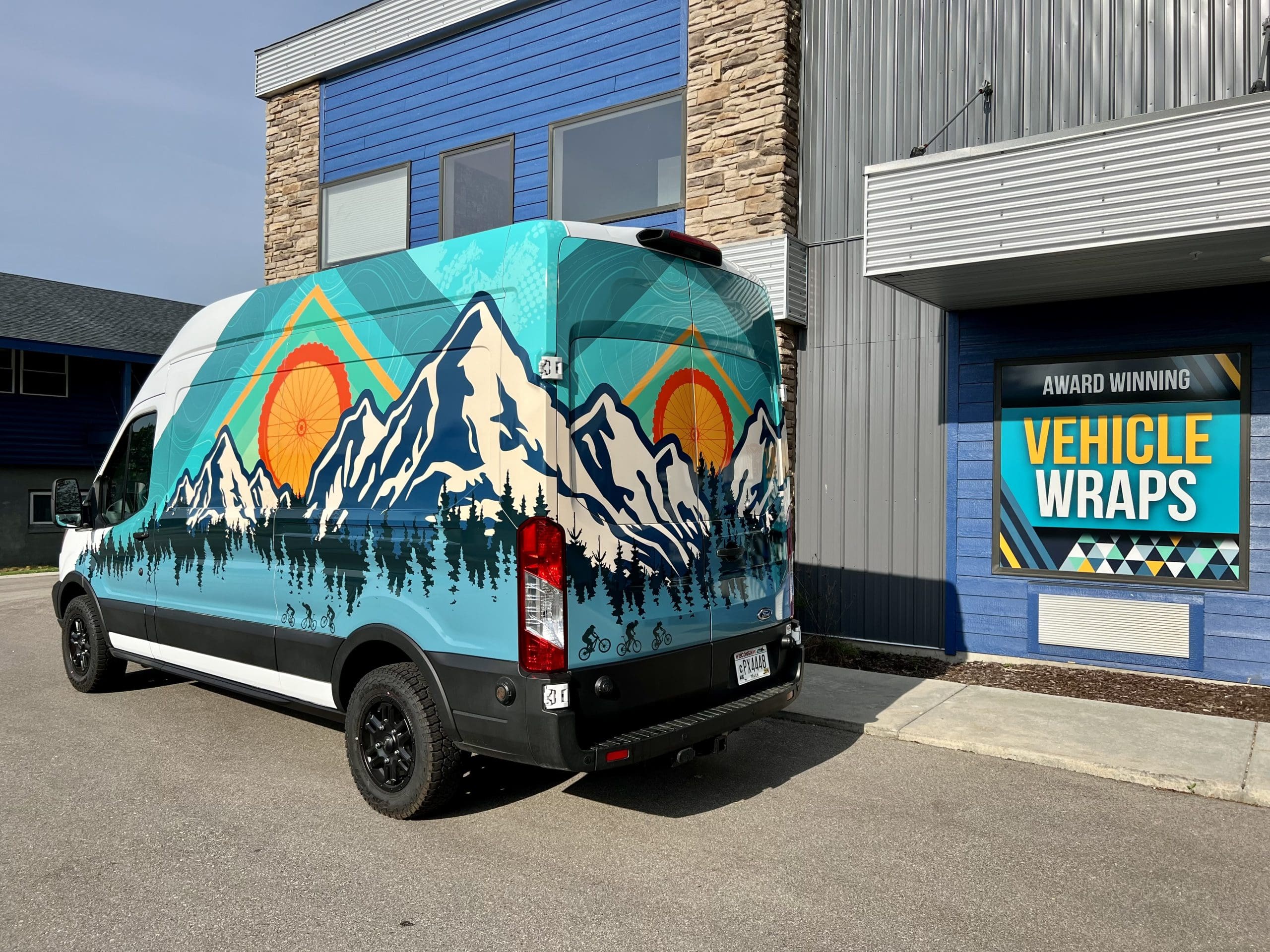 Colorado Mountains Fleet Graphics Vehicle wrap designed by Madison Graphics Company parked in front of the design building with a window sign saying 