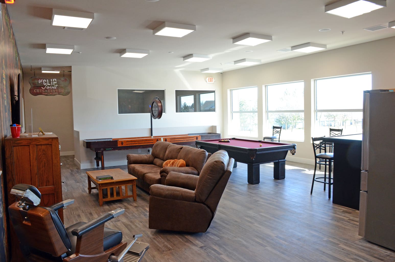 Club recreation room for Madison Graphics Company showing couches facing a wall TV, shuffle board and pool table.