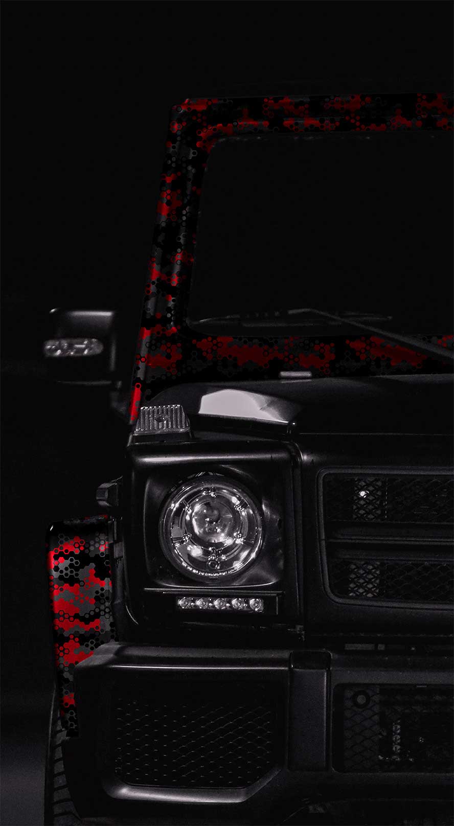 Right car headlight of a Jeep with red and grey computer camouflage