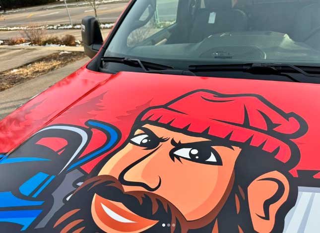 Top of a vehicle hood with a cartoon drawing of a man with a red beanie