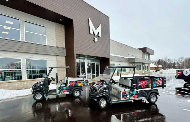 Two electric golf carts parked in front of Madison Graphics Company building with colorful fun bowling sports wrap on the carts.